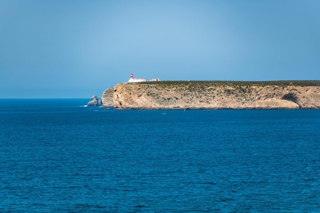 Scenic view of the Sagres lighthouse perched on cliffs above the blue Atlantic Ocean in Faro, Portugal.