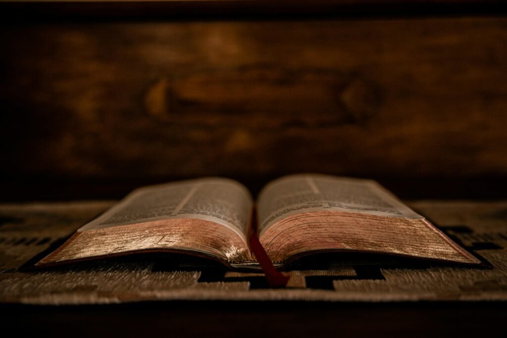 A dimly lit open Bible displayed on a wooden altar, highlighting its pages.